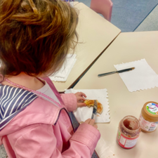 Student putting peanut butter and jam on a piece of toast